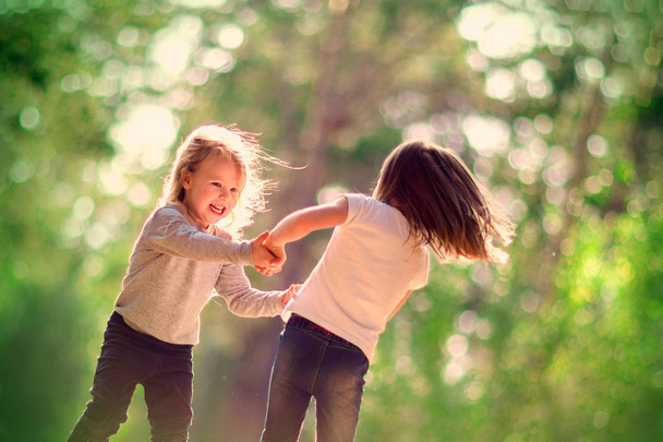 Two little girls dancing and having fun together outdoors - Foto, afbeelding