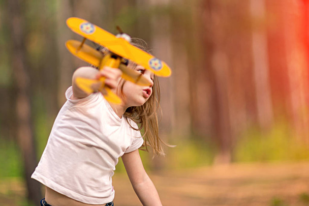 Little girl playing with toy airplane outdoors. Dreams of traveling - Φωτογραφία, εικόνα