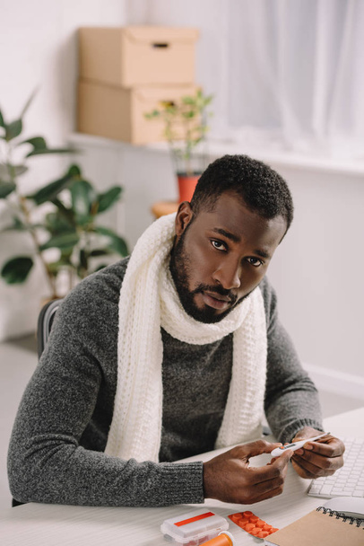 beteg afrikai amerikai férfi, gazdaság elektronikus hőmérő-kezelés a munkahelyen - Fotó, kép