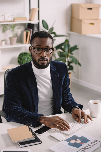 stylischer afrikanisch-amerikanischer Geschäftsmann tippt im Büro auf Computertastatur - Foto, Bild