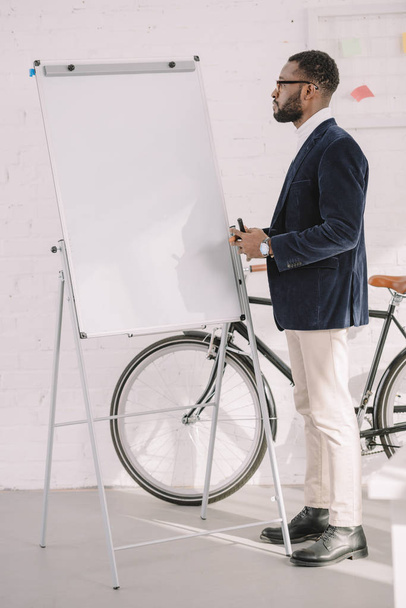 afrikkalainen amerikkalainen liikemies työskentelee whiteboard toimistossa polkupyörän kanssa
 - Valokuva, kuva