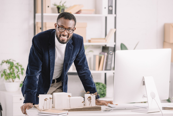 menestyksekäs afrikkalainen amerikkalainen arkkitehti työskentelee liikerakennusten mallin ja tietokoneen kanssa modernissa toimistossa
  - Valokuva, kuva