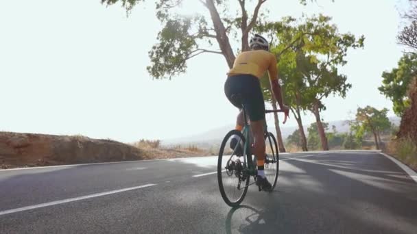 Dağ bisiklet bisikletçi yokuş yukarı bir yolda sürme. Arka görüş. Yaz günü. ağır çekim - Video, Çekim