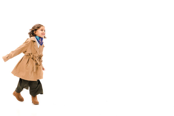 schönes kleines Kind im Trenchcoat läuft vereinzelt auf weiß - Foto, Bild
