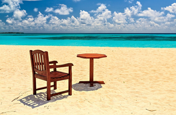 Chaises et table sont sur la plage
 - Photo, image