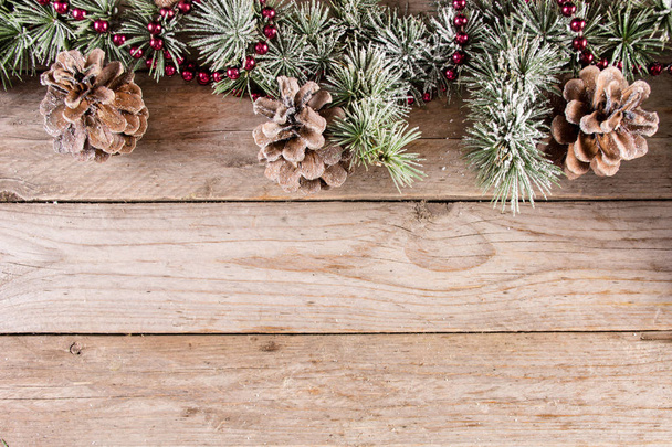 Weihnachten und Neujahr Urlaub Hintergrund mit Tanne und Tannenzapfen mit Schnee auf Holz Retro-Hintergrund. Raum für Text und Gestaltung. Nahaufnahme, selektiver Fokus - Foto, Bild