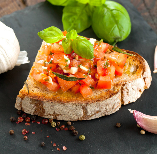 bruschetta, on slices of toasted baguette garnished with basil - Foto, afbeelding