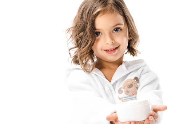 lindo niño en blanco albornoz mostrando crema corporal en manos aisladas en blanco
 - Foto, Imagen