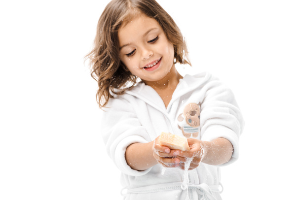 retrato de niño sonriente en albornoz lavándose las manos con jabón aislado en blanco
 - Foto, Imagen