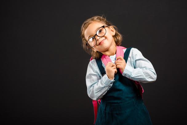 portrait of adorable schoolchild in eyeglasses with backpack isolated on black - Foto, Bild