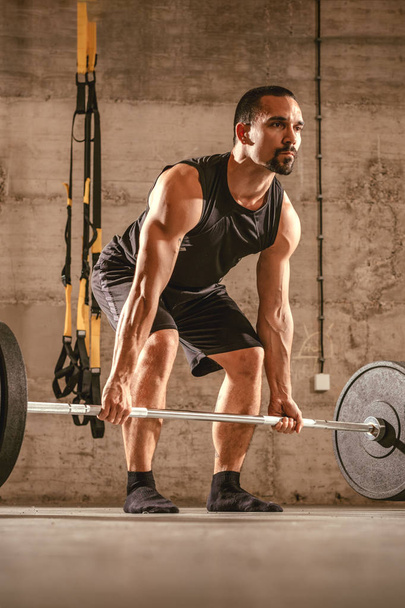 Handsome young muscular man doing squat exercise with barbell at the gym. - Foto, imagen