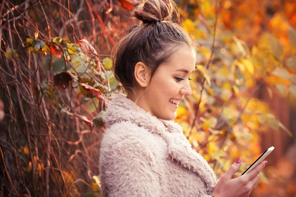 Retrato de mujer feliz atractiva mientras charla con su amada en su teléfono inteligente, parque al aire libre disparar
 - Foto, Imagen