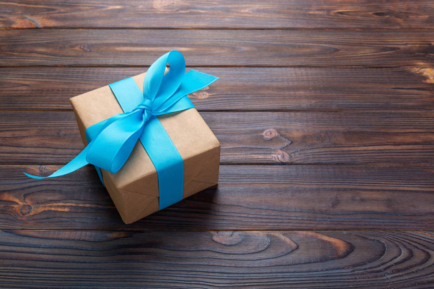 κουτί δώρου χαρτί με μπλε κορδέλα σε σκούρο φόντο ξύλου. το Top view με αντίγραφο χώρου. - Φωτογραφία, εικόνα