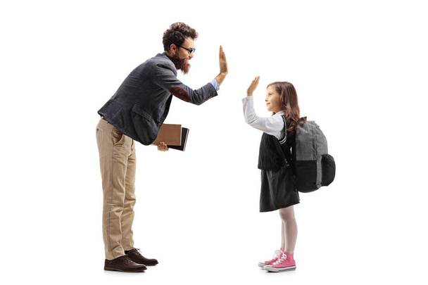 Full length profile shot of a teacher high-fiving a schoolgirl isolated on white background - Photo, Image