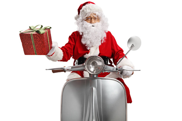 Santa Claus with a present riding a vintage scooter isolated on white background - Foto, imagen