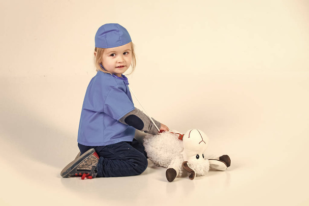 small boy in doctor uniform playing vet with toy animal - Foto, Imagem