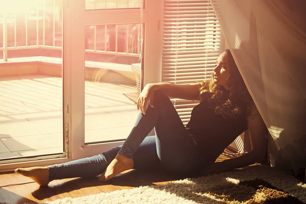 Girl in jeans relax on floor at door window indoor. Fashion, beauty, look, makeup. Daydreaming, leisure, lifestyle concept - Foto, afbeelding