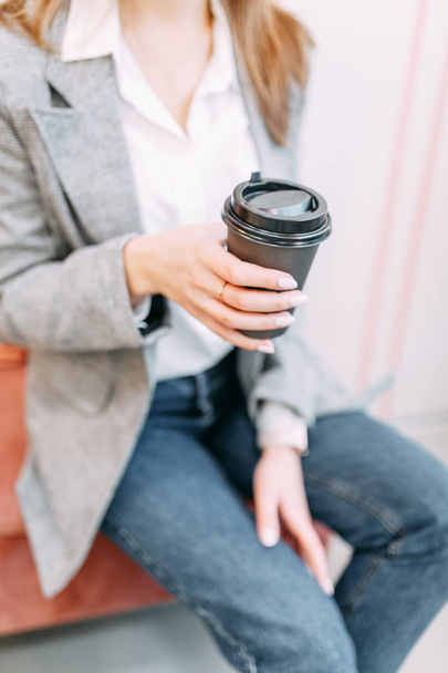 Chica blogger con café sentada en una cafetería y trabajando. Portátil y teléfono en mano. Estilo de negocio en ropa
. - Foto, Imagen