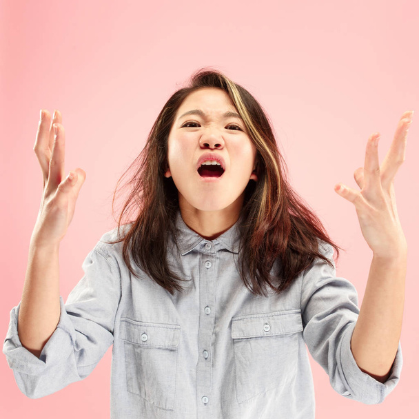 The young emotional angry woman screaming on pink studio background - Foto, Imagen