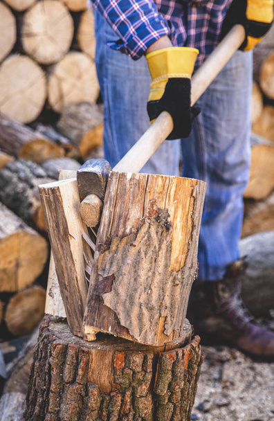 Man holding an industrial ax. Ax in hand. A strong man holds an ax in his hands against the background of chainsaws and firewood. Strong man lumberjack with an ax in his hand. Chainsaw close up. - Photo, Image