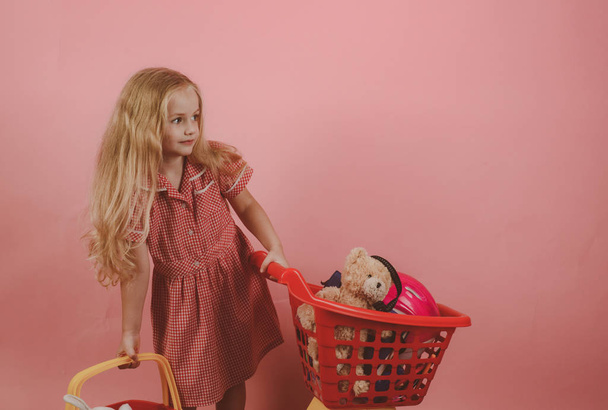 Retro inspired. Little shopaholic with shopping cart. Little girl shopping. Small girl in shop. Small shopper. I love shopping - Foto, afbeelding