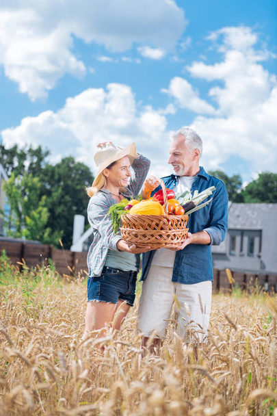 Beautiful stylish wife wearing beige hat standing hear husband holding harvest - Foto, immagini