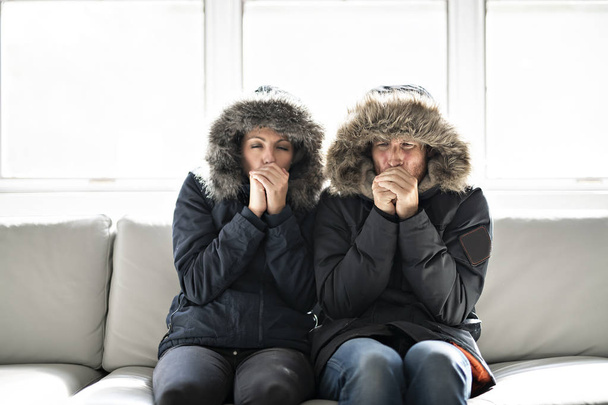 Couple have cold on the sofa at home with winter coat - Fotó, kép