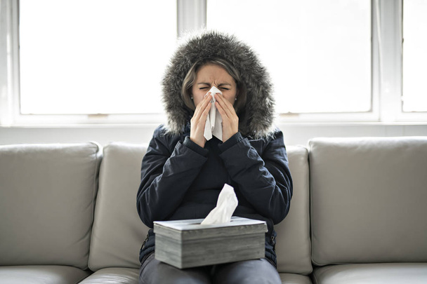 Woman have flu on the sofa at home with winter coat - Φωτογραφία, εικόνα