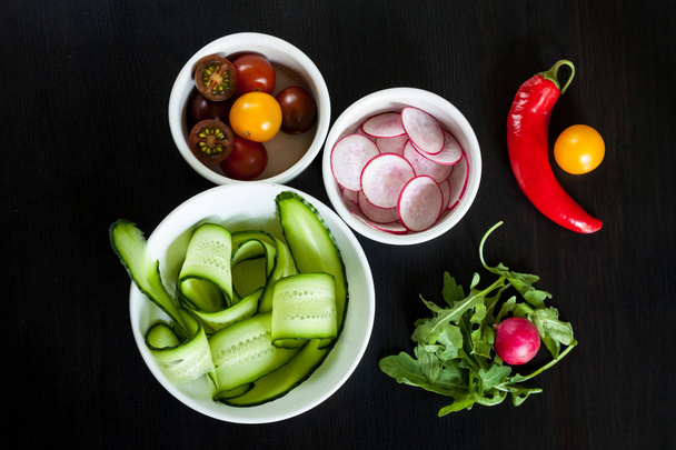Bowls with ingredients for salad on a dark background. - Photo, Image