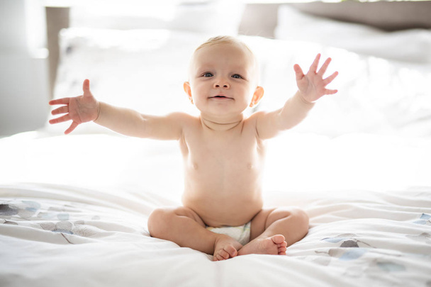 Cute baby girl sit on white sheet at home - Foto, imagen
