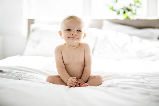 Cute baby girl sit on white sheet at home - Zdjęcie, obraz