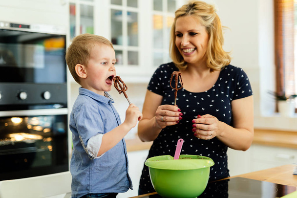 Smart cute child helping mother in kitchen preparing cookies - Foto, Bild