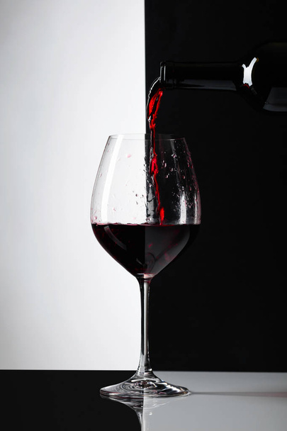 Rotwein wird in ein Glas gegossen. reflexiven Hintergrund, kopieren Sie Platz für Ihren Text. - Foto, Bild