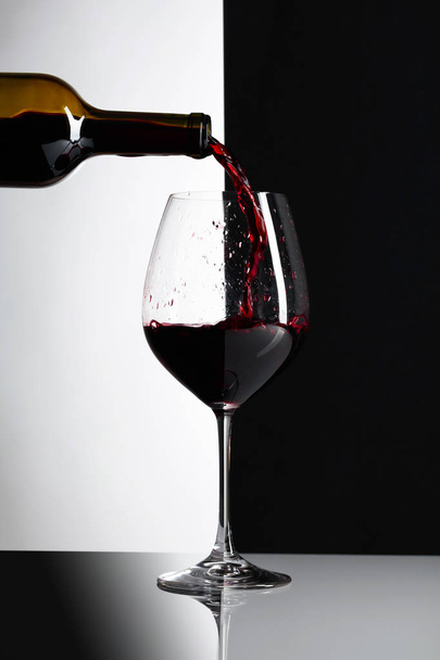 το κόκκινο κρασί χύνεται σε ένα ποτήρι. - Φωτογραφία, εικόνα