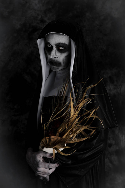 портрет страшної злої черниці, що носить типову чорно-білу звичку, з сухим букетом квітів в руках
 - Фото, зображення