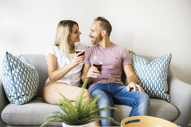 Relaxed young couple watching tv and drinking beer at home - Fotoğraf, Görsel