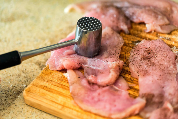 Χτυπάει το ωμό κρέας με μεταλλικό σφυρί κοντά - Φωτογραφία, εικόνα