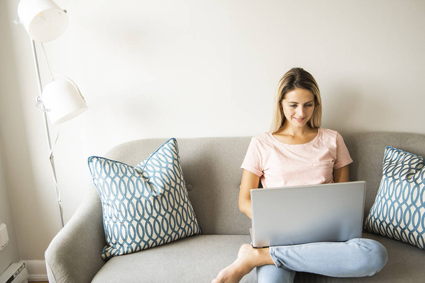 woman with a laptop on sofa at home - Foto, Imagem