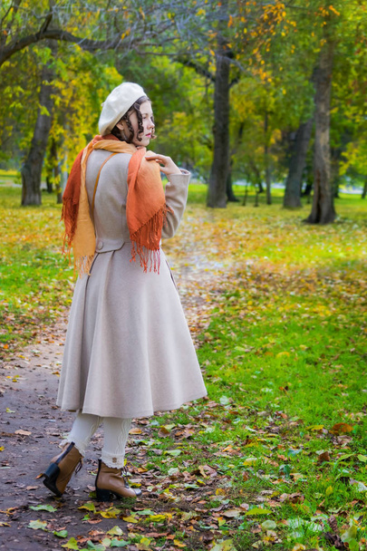 Girl with a surprised look in her coat and take on a walk in the autumn afternoon, view from the back. - Foto, Bild