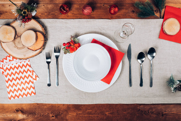 木製のテーブル上の美しい冬の装飾とカトラリー トップ表示はクリスマス ディナーを提供しています。休日背景 whith プレート、銀製品やモミの木の装飾品 - 写真・画像