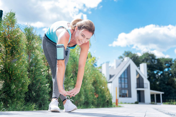 Mujer de pelo rubio delgada y en forma estirando las piernas después de correr por la mañana
 - Foto, Imagen
