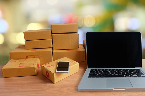 Mobile phone, laptop computer, and Product Box, On wooden floor with blurred Colorful bokeh background, Online shopping, work at home, e commerce - Фото, зображення