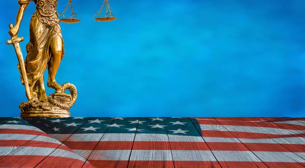 Άγαλμα της δικαιοσύνης και των Ηνωμένων Πολιτειών σημαία στο ξύλινο πάτωμα με φόντο μπλε του ουρανού - Φωτογραφία, εικόνα