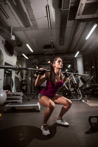 Erős nő csinál quats, miközben bár súly a vállán sportruházat. - Fotó, kép