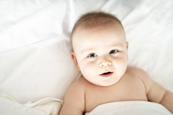 A happy baby lying on white sheet - Foto, immagini