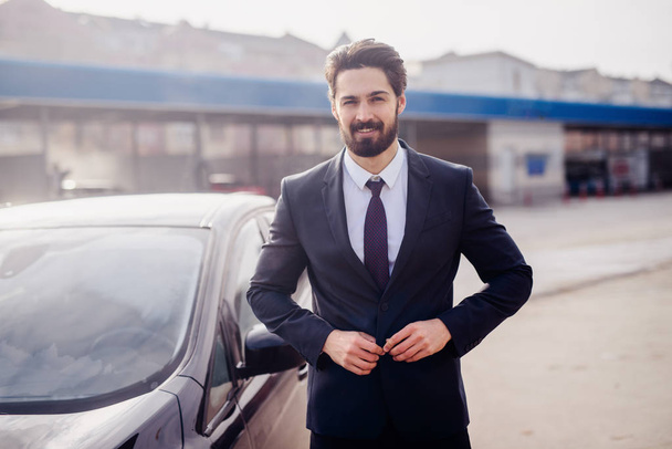 Un hombre de negocios satisfecho posando junto a su coche limpio. concepto de lavado de coches
. - Foto, Imagen