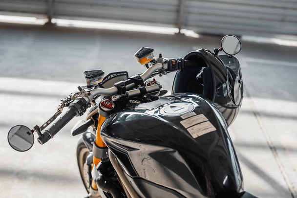 Close up of black glossy helmet at motorcycle handlebars. Urban background. - Photo, image