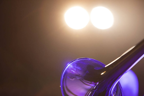 Частина тромбону під час концерту з двома яскравими сценічними вогнями
 - Фото, зображення