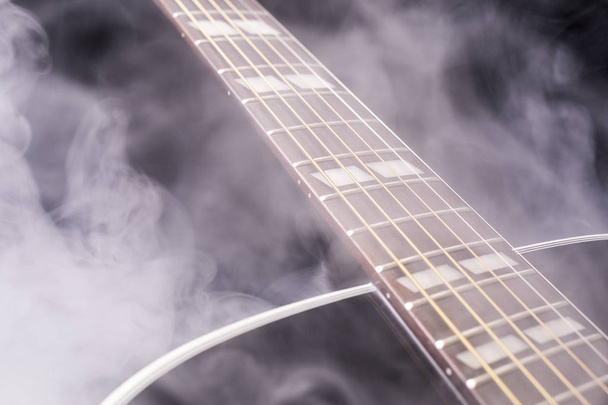 Una parte de una guitarra clásica negra en humo sobre un fondo negro
 - Foto, Imagen