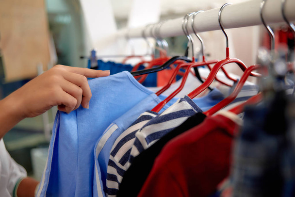 Concentration sélective de la main féminine tenant cintre avec de nouveaux vêtements dans le magasin
 - Photo, image